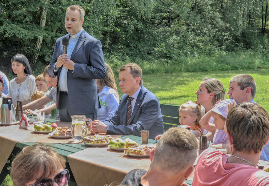 Minister Błaszczak i ks. Harkiewicz żegnają uchodźców. Źródło: ro.com.pl 